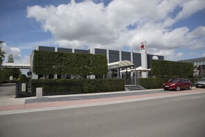 Stunning entrance with a glass canopy, surrounded by manicured hedges and a secure fence.