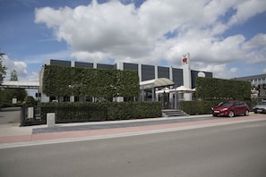 Stunning entrance with a glass canopy, surrounded by manicured hedges and a secure fence.