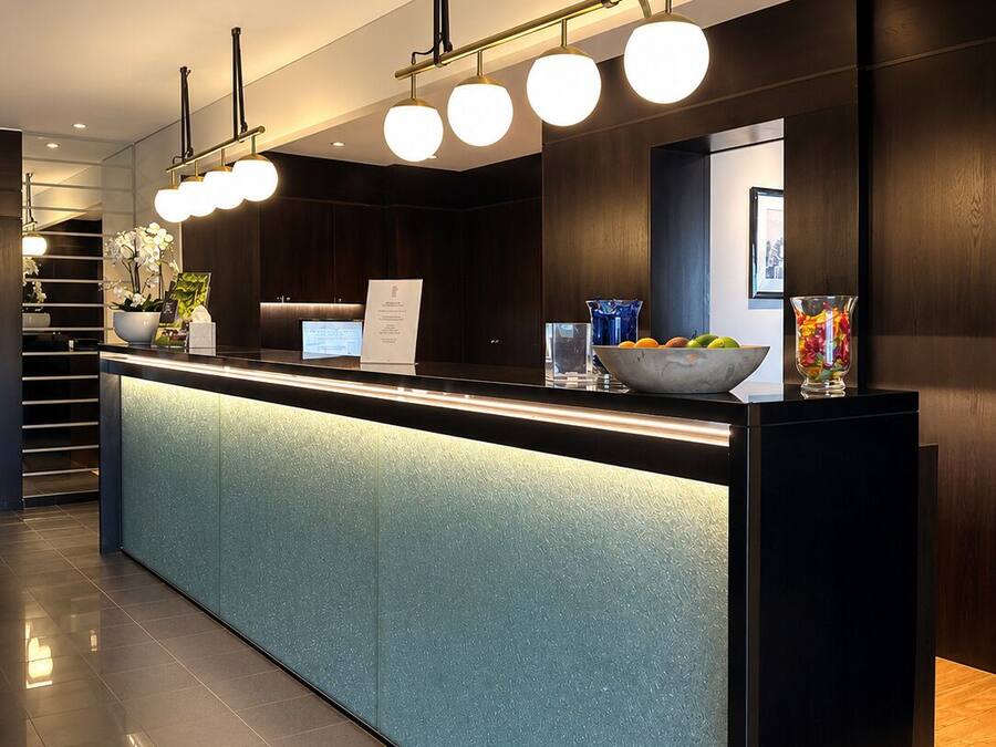 A modern reception desk with a glass top, overhead lighting, and a digital display.