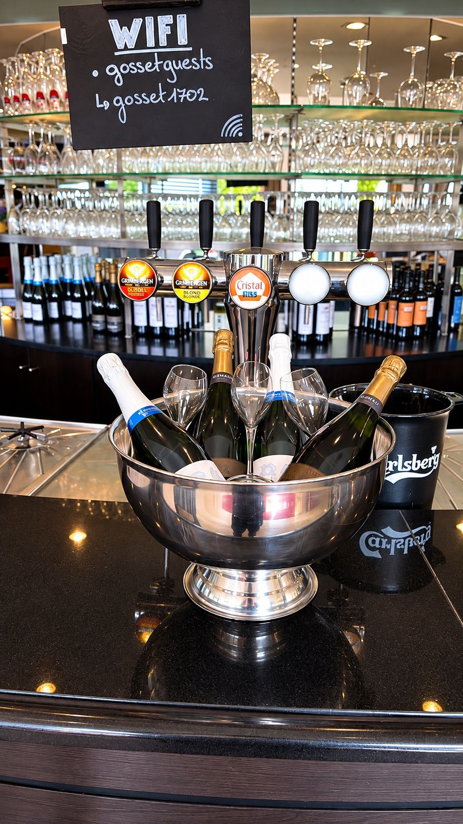 A bar area with a WIFI sign, a selection of wine bottles, and a bowl of champagne glasses.