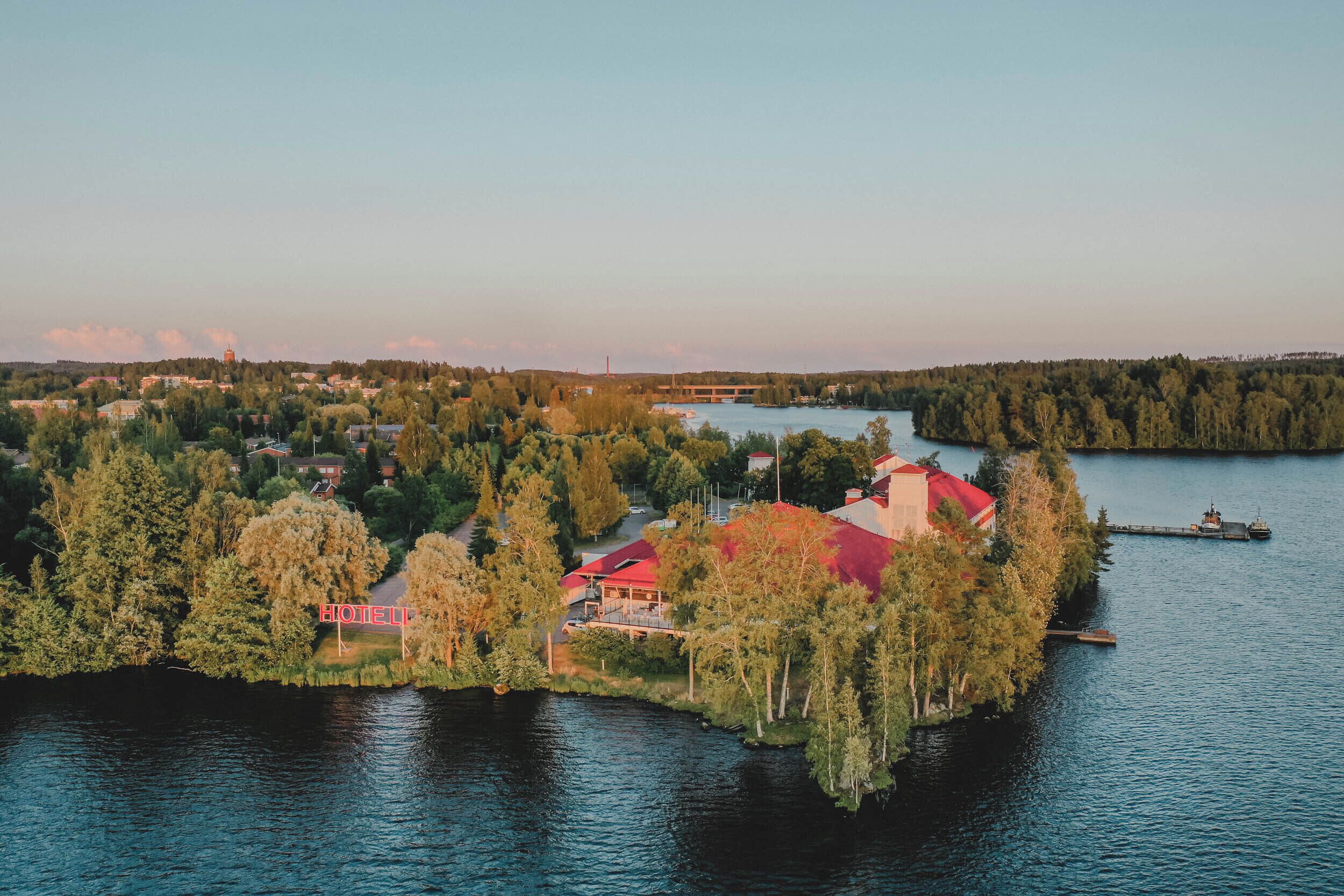 An island hotel with multiple buildings, surrounded by water and trees.