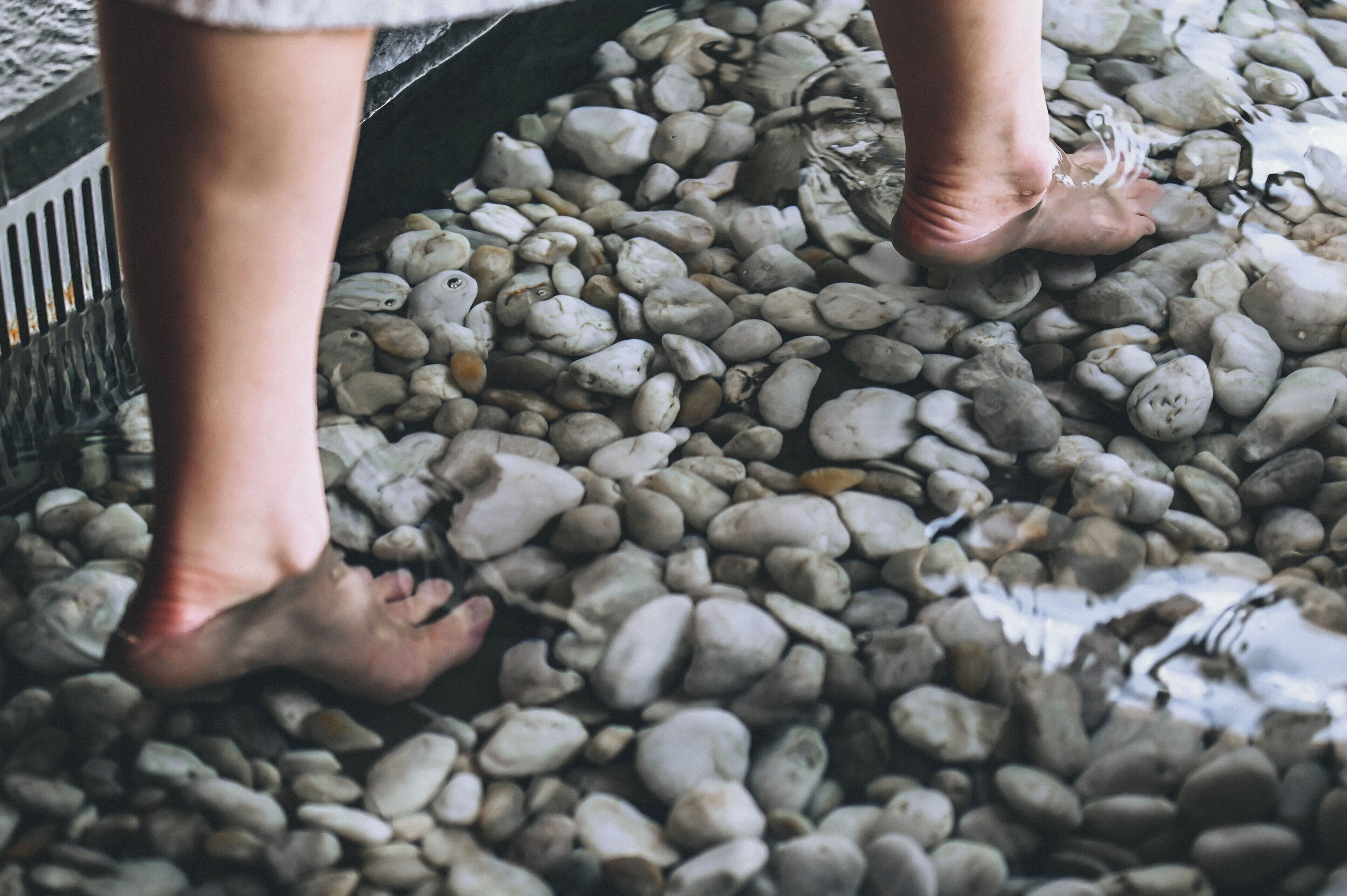 A close-up of feet standing on pebbles.