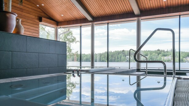 A glass-enclosed hot tub with a view of a lake and forest. - Kumpeli Spa (Heinola)