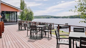 A wooden deck with outdoor seating overlooking a lake. - Kumpeli Spa (Heinola)