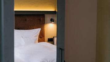 A hotel room with a bed, a nightstand, and a wall-mounted lamp.