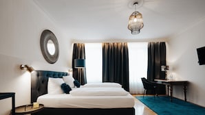 Ein Hotelzimmer mit Bett, Nachttisch, Lampe und Schreibtisch mit Stuhl.