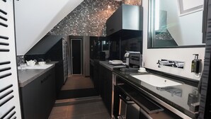 A modern kitchen with a dark countertop, a sink, a coffee machine, and a large mirror. - Boutique Villa am Ruhrufer Retreat (Muelheim an der Ruhr)