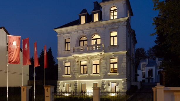A large, historic building with multiple windows and a balcony, surrounded by a well-maintained fence. - Boutique Villa am Ruhrufer Retreat (Muelheim an der Ruhr)