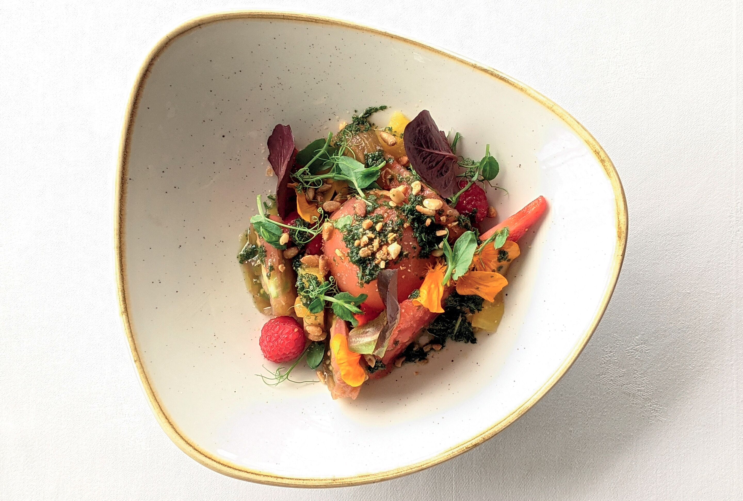 Un tazón de ensalada colorida con diferentes verduras y nueces.