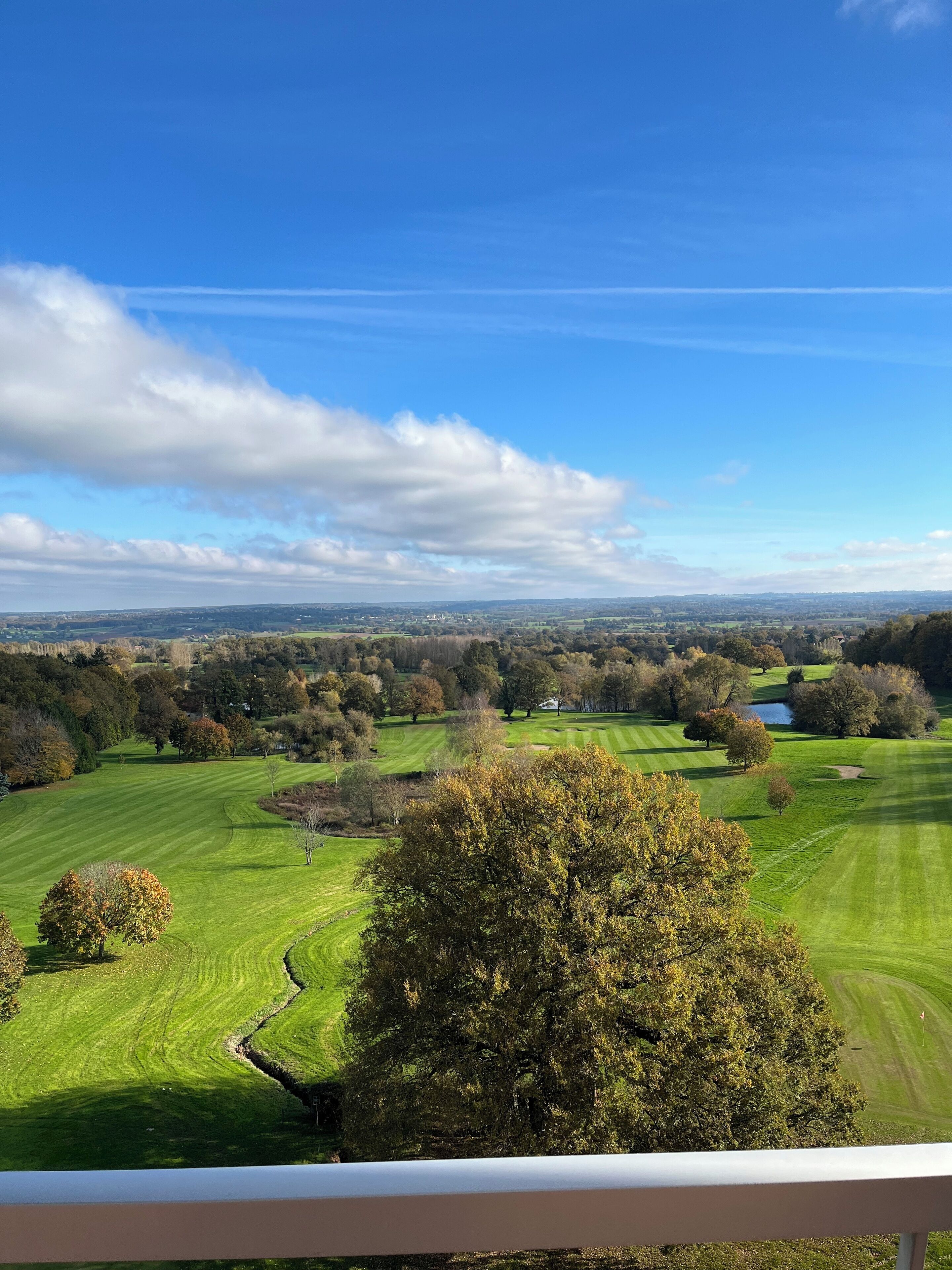 A panoramic view of a golf course with a clear sky and distant landscape.