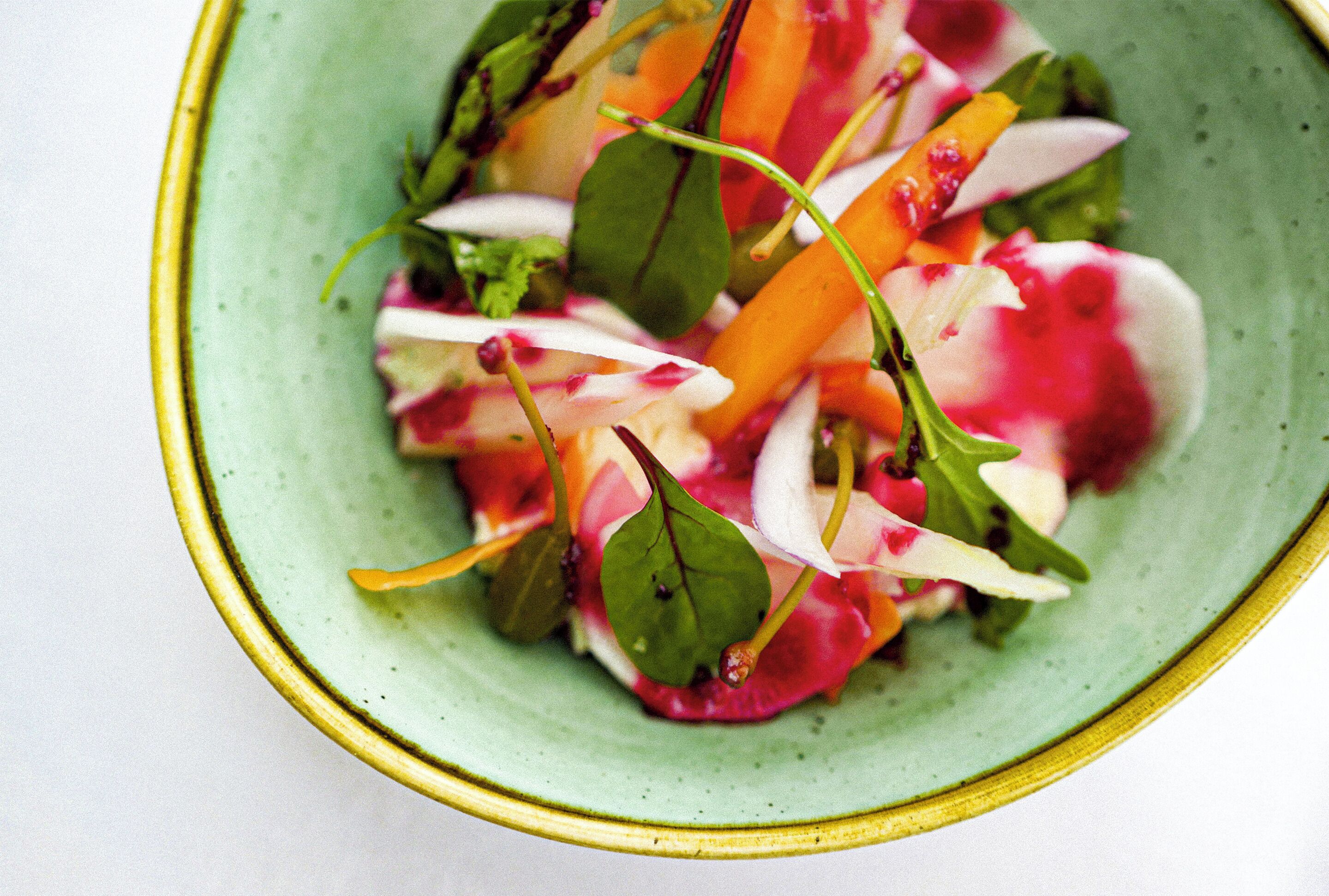 En skål med sallad innehållande olika grönsaker och bladgrönt.