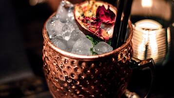 Una taza de cobre llena de hielo y una bebida, adornada con pétalos de rosa.