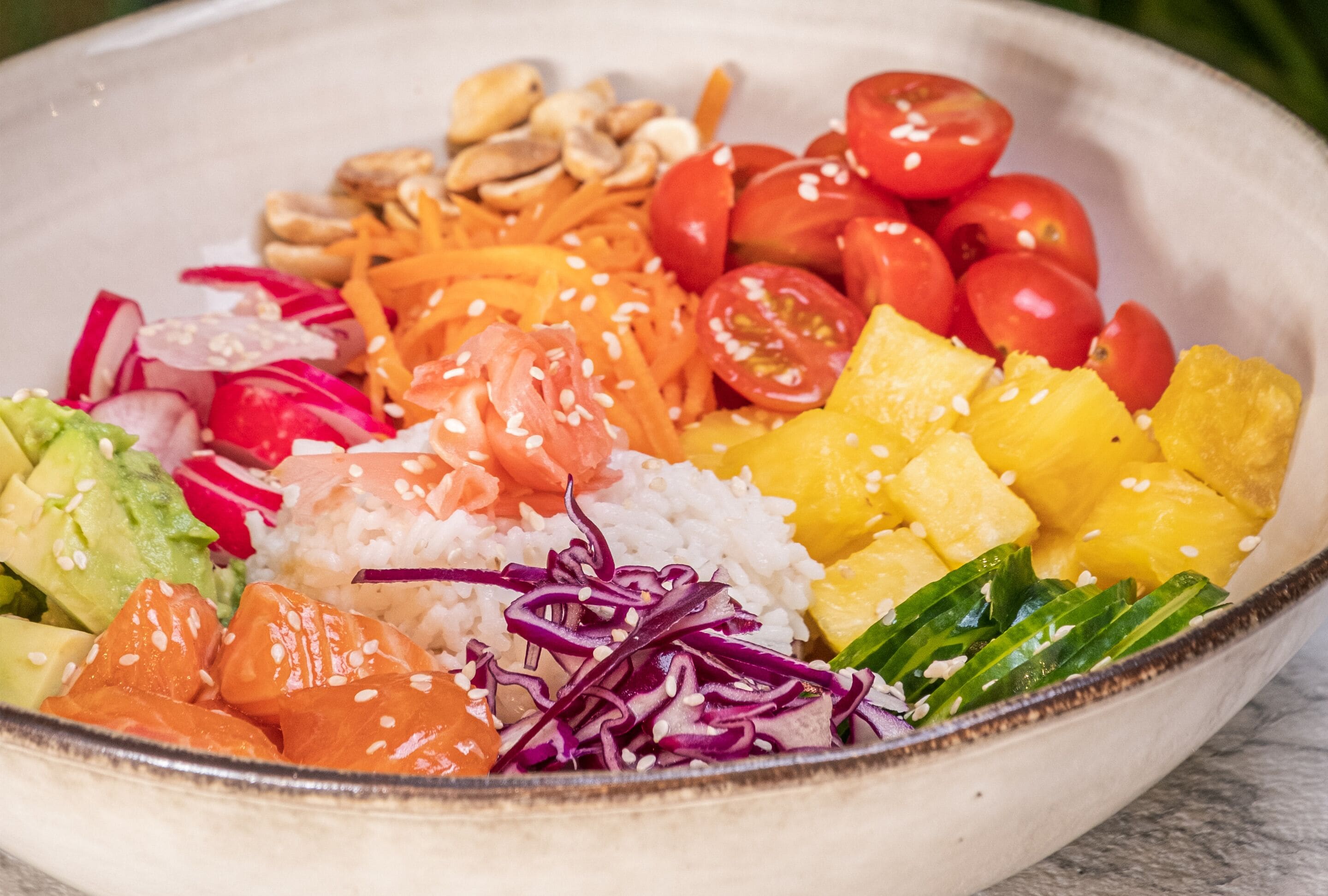 A bowl of colorful salad with various ingredients like avocado, salmon, and vegetables.