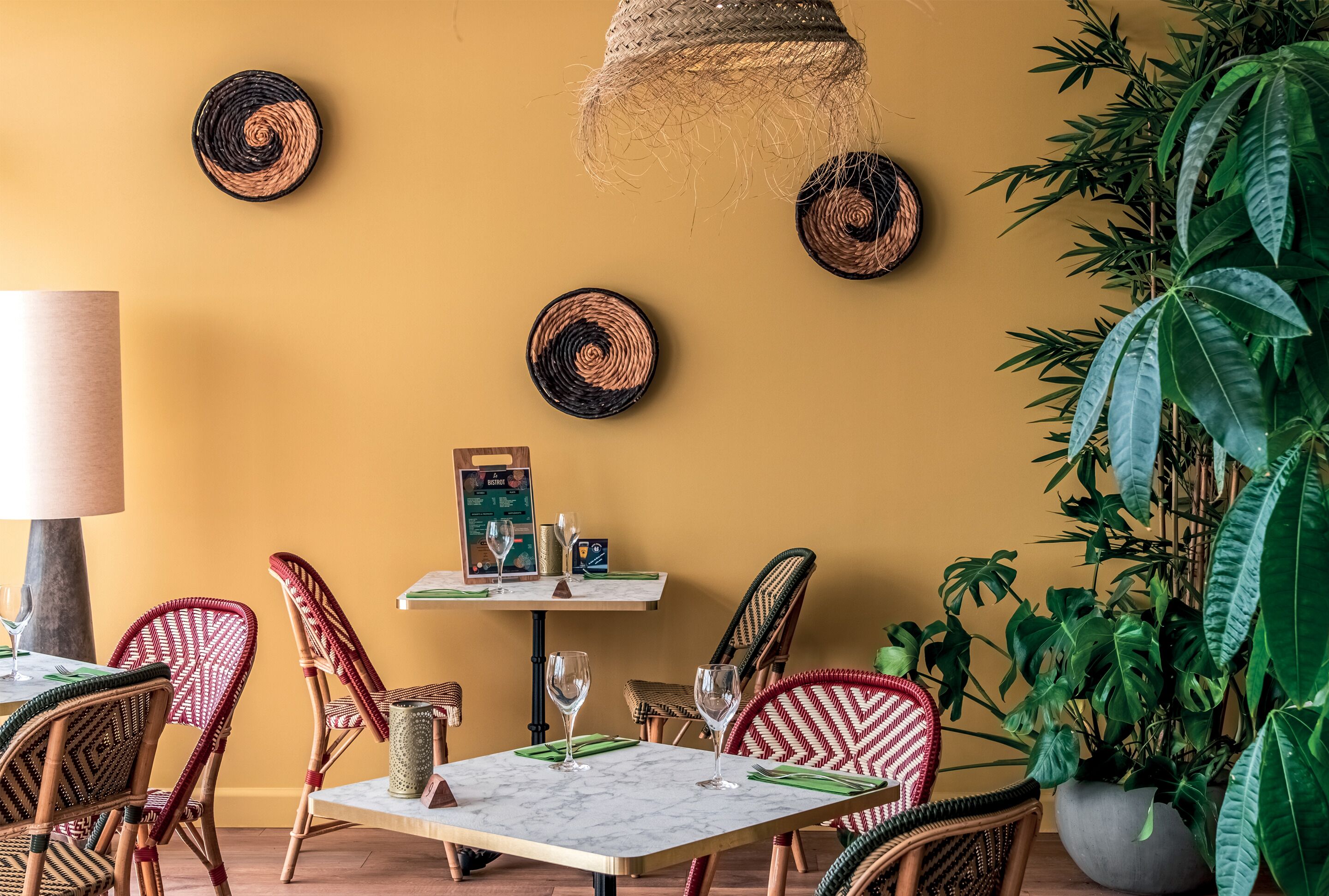 A dining area with wicker chairs, a table with a menu, and a hanging light fixture.