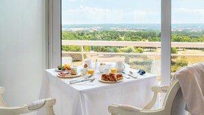 A table set with breakfast items and a view of a green landscape through a window.