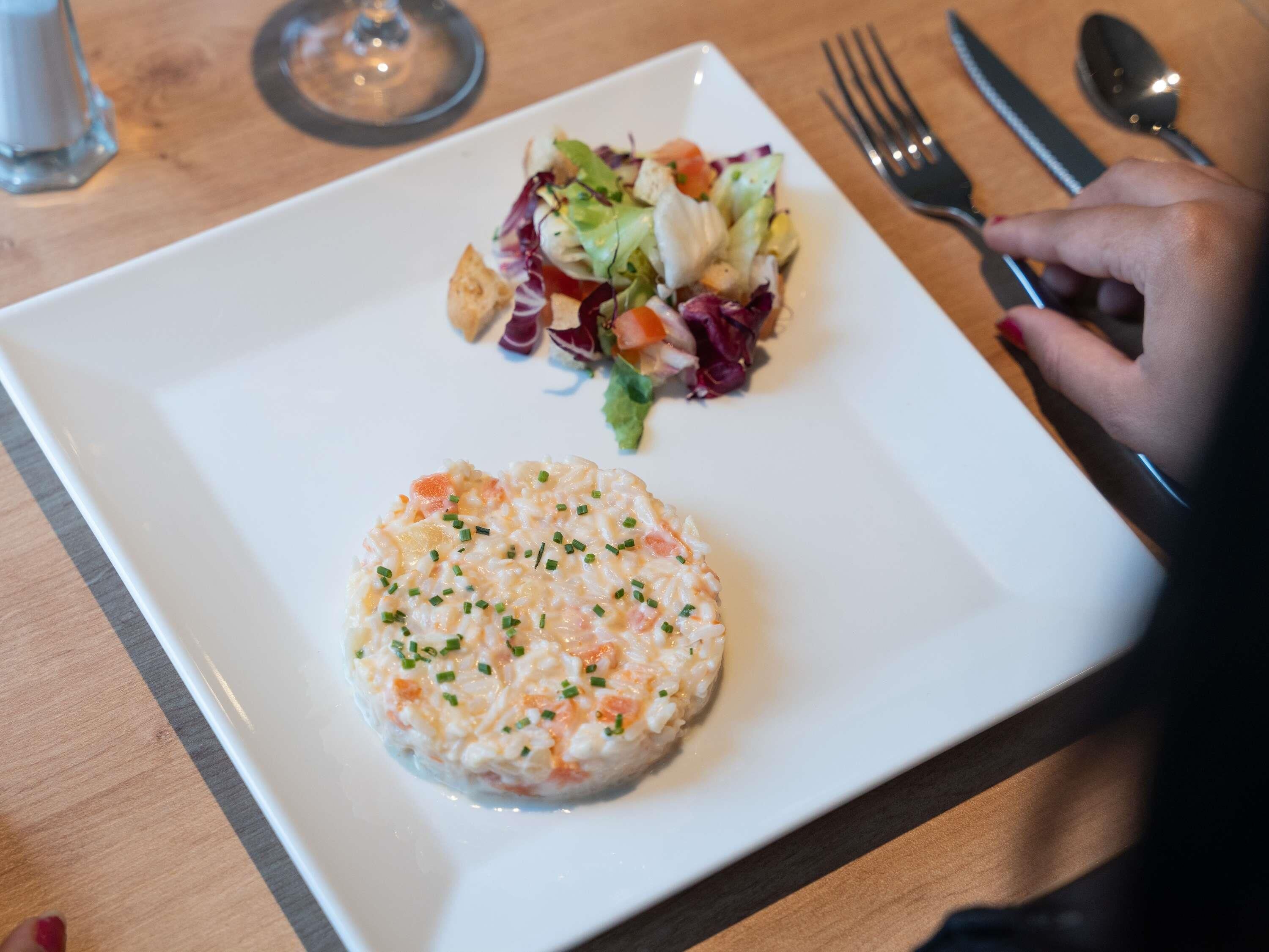 Une assiette contenant une salade et un aliment de forme ronde, le tout présenté sur une assiette blanche.