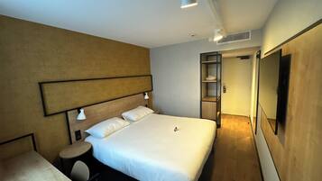 A hotel room with a large bed, bedside tables, a desk, and a wardrobe.