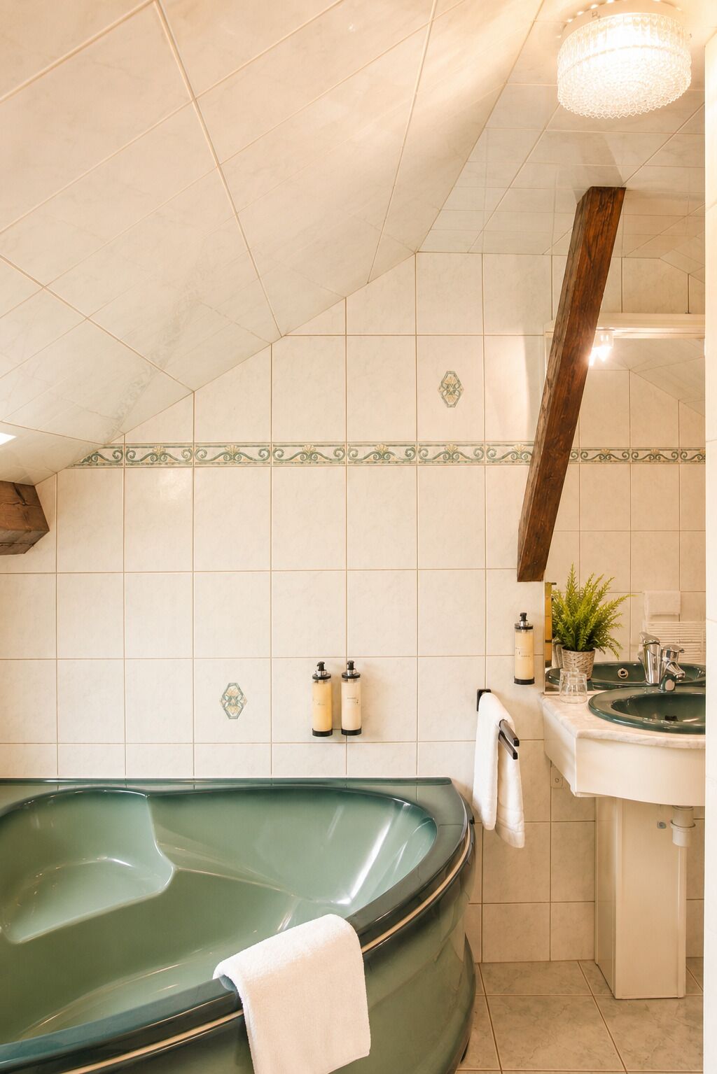A bathroom with a green bathtub, a sink, and two bottles of lotion on the wall.