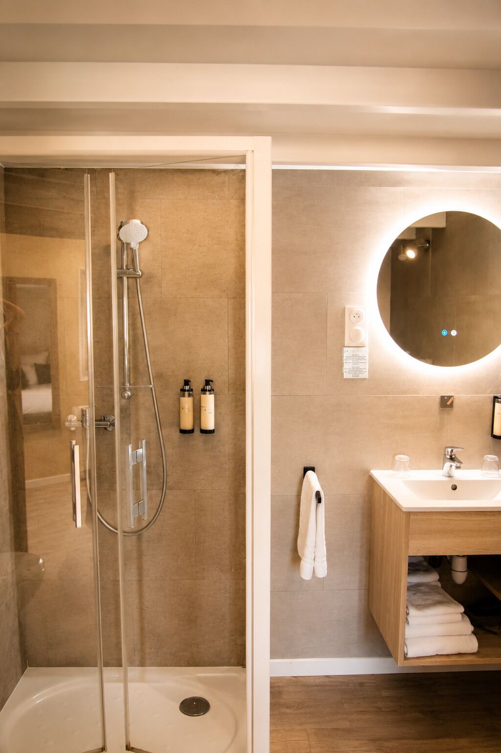 Een moderne badkamer met een glazen douchecabine, een houten wastafelmeubel met spiegel en een handdoekrek.