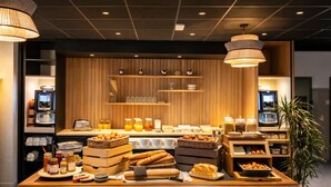 Ein reichhaltiges Buffet mit verschiedenen Speisen und Getränken, einer Kaffeemaschine und einem Fernsehbildschirm.