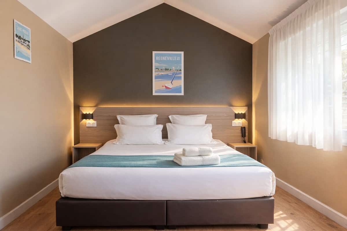 A bedroom with a bed, two bedside tables, a headboard, a poster, and a window with curtains.