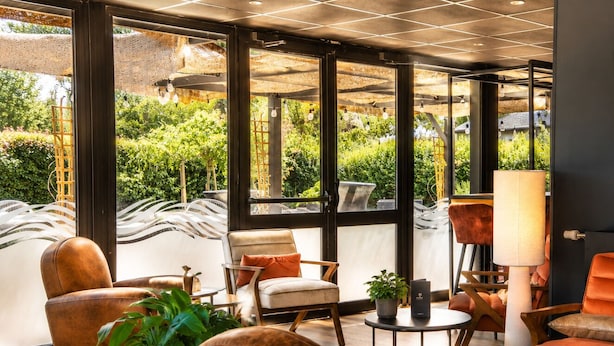 Ein modernes Interieur mit großen Fenstern, Ledersesseln, einem runden Tisch und einem Blumentopf.