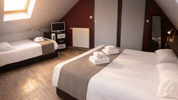Una habitación de hotel con dos camas, televisión, cómoda, radiador y tragaluz.