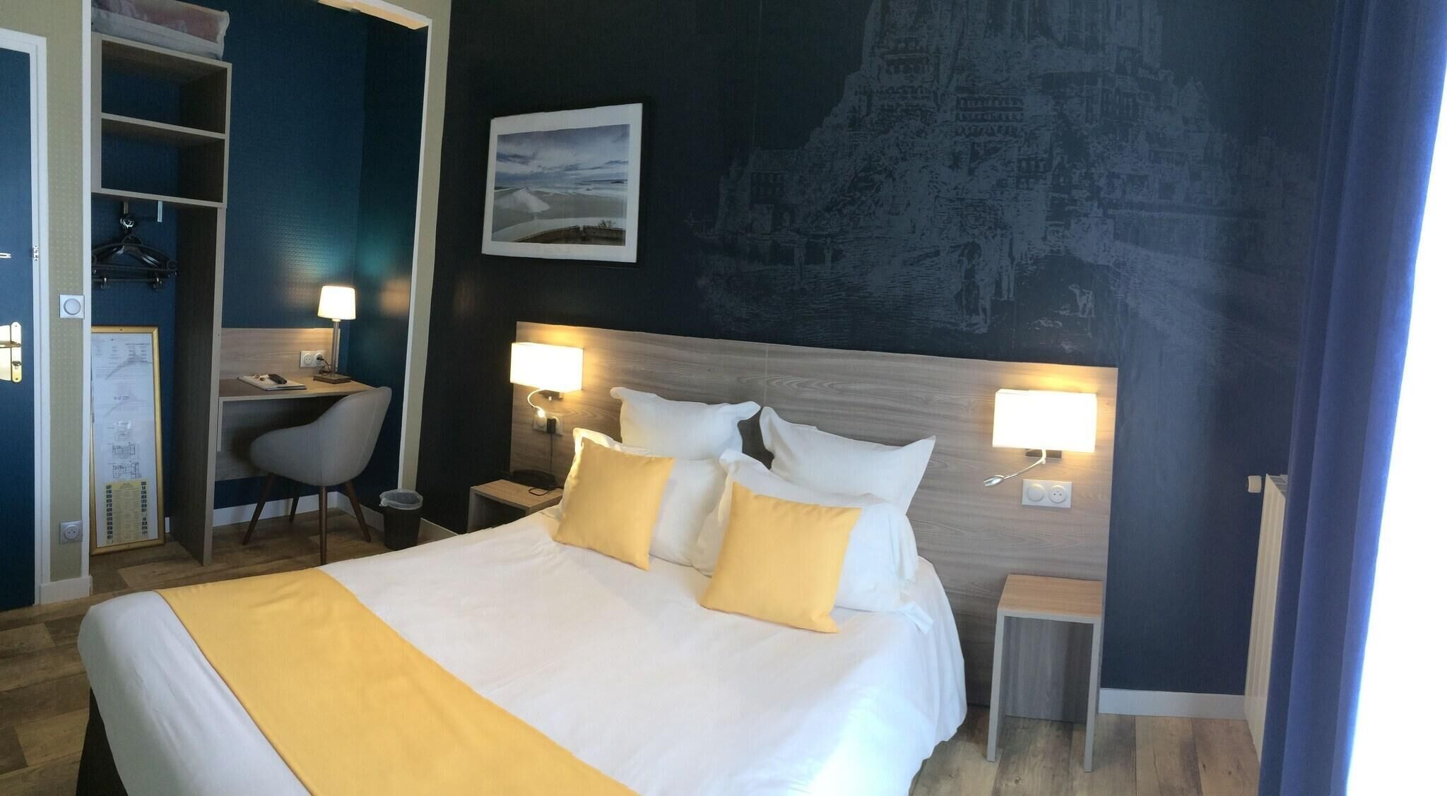 Una habitación de hotel con cama, lámparas de noche, escritorio y una silla.