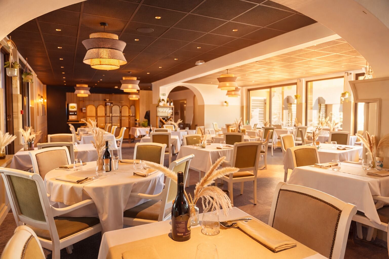 En restaurant med runde borde, hvide dugge og stole.