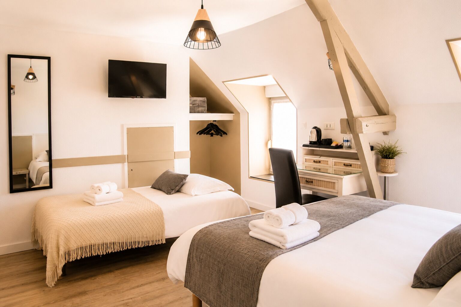 Quarto de hotel com duas camas, televisão, escrivaninha e uma cadeira.