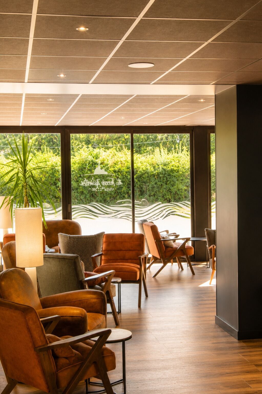 A modern interior with a seating area, large windows, and a view of greenery.