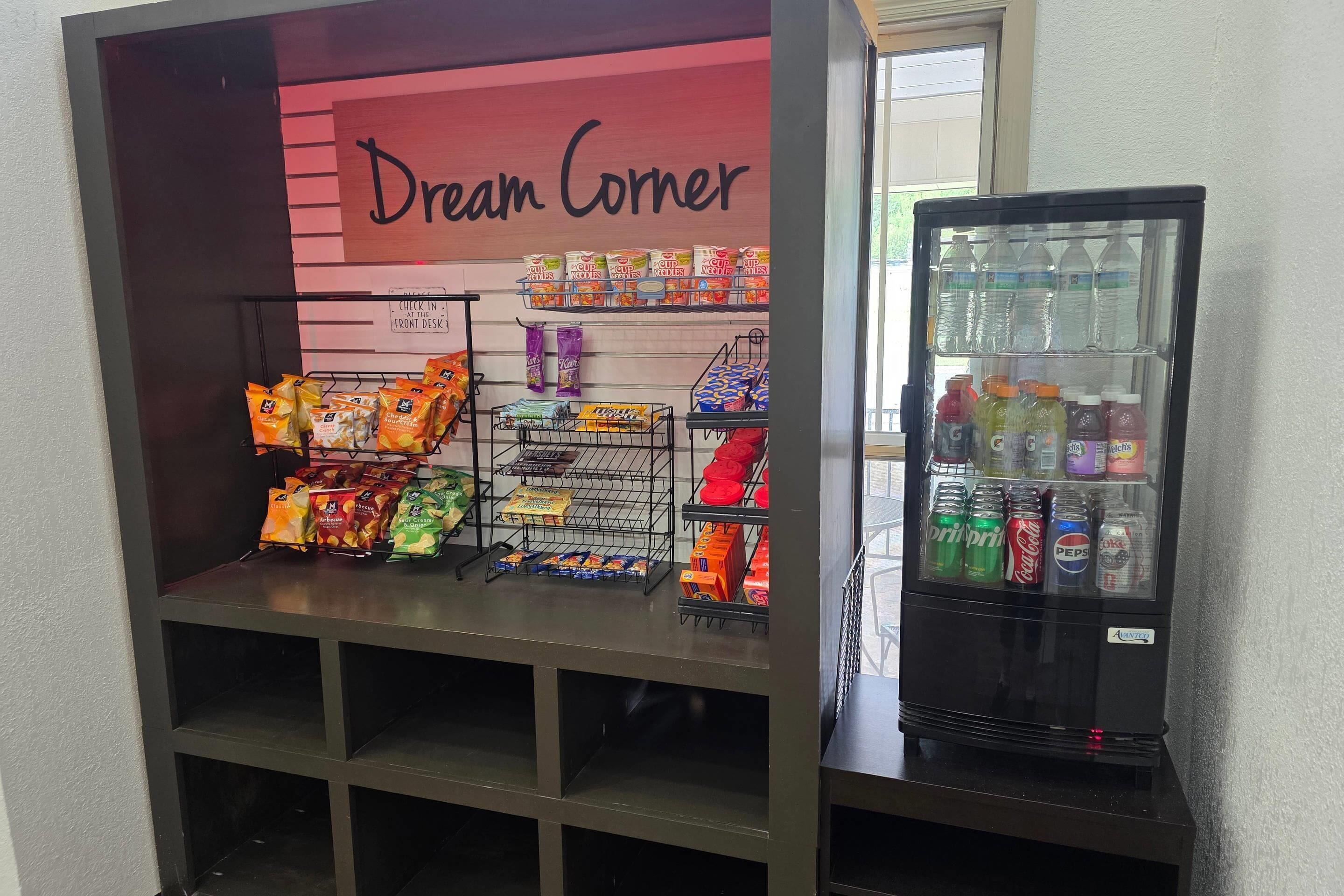 Una exhibición de snacks con diversos alimentos envasados y un dispensador de bebidas.