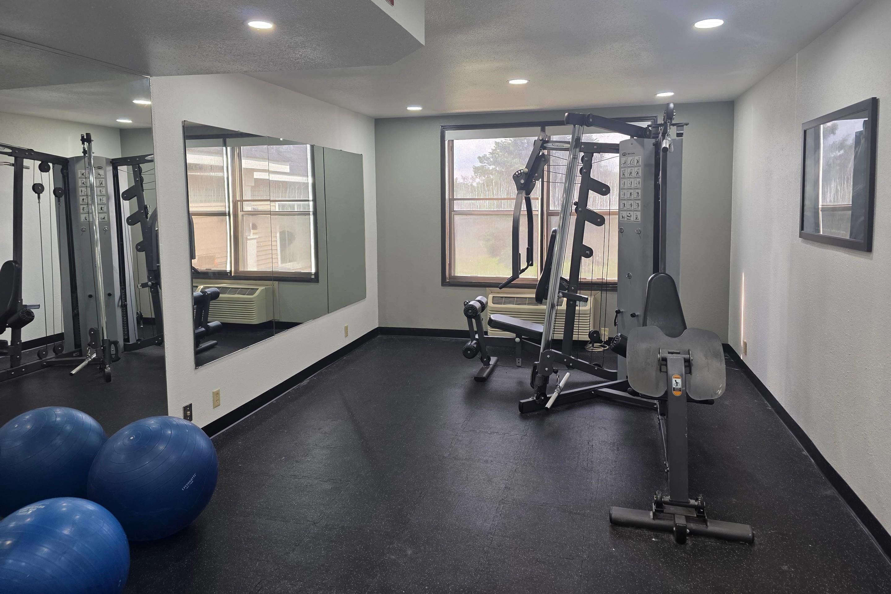 A gym with exercise equipment, a large mirror, and exercise balls.