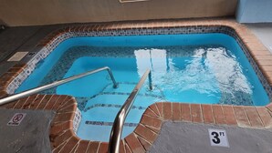 A hot tub with a tiled edge, a metal ladder, and a 'NO DIVING' sign.