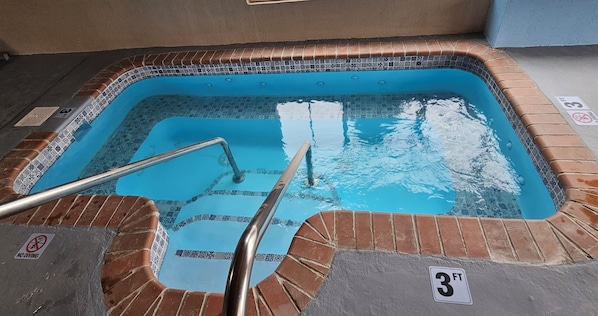 Un jacuzzi con borde de azulejos, una escalera metálica y un letrero que dice 'NO DIVING'.