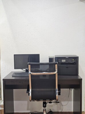 Un espacio de trabajo con un monitor de computadora, teclado e impresora sobre un escritorio.