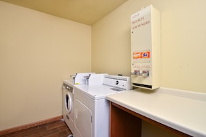 A laundry area with a washing machine, dryer, and a soap dispenser on the wall.