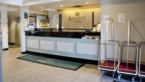 A hotel reception area with a reception desk, a digital screen, and a sign indicating amenities like Wi-Fi and a business center. - Quality Inn Midway (Bethel)