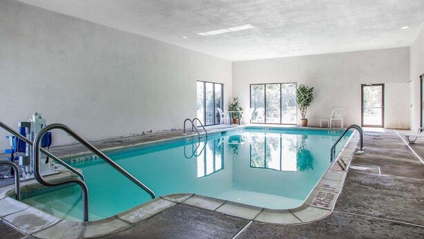 An indoor swimming pool with clear water, a diving board, and a lifeguard chair. - Quality Inn Midway (Bethel)