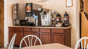 A kitchenette with a refrigerator, a coffee machine, and a microwave. There are two white chairs and a table in front of the kitchenette. - Quality Inn Midway (Bethel)