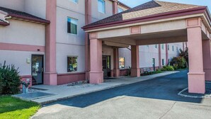A multi-story hotel with a covered entrance and a parking area. - Quality Inn Midway (Bethel)