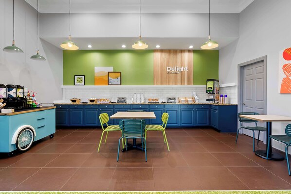 Une cuisine moderne avec des meubles bleus, un îlot central doté d’une machine à café et deux chaises.