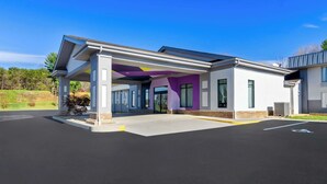 A modern building with a covered entrance, large windows, and a parking lot. - Spark by Hilton Daleville Roanoke North (Daleville)