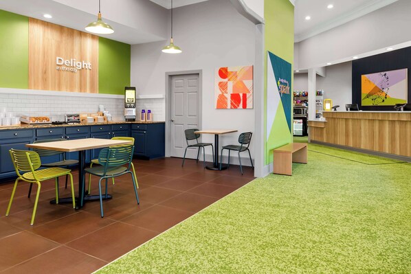 A modern cafe with a wooden counter, green walls, and a green carpeted area. - Spark by Hilton Daleville Roanoke North (Daleville)