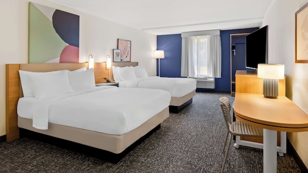 A hotel room with two beds, a desk, a chair, a TV, and artwork on the walls. - Spark by Hilton Daleville Roanoke North (Daleville)