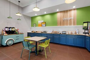 Une cuisine moderne avec des armoires de couleur turquoise, un mur d’accent en bois et un coin café.