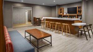 Un área de bar moderna con taburetes, una barra y un televisor.