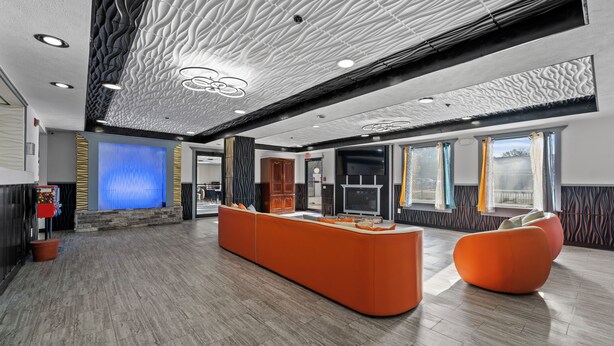 A spacious lobby with a central seating area, a fireplace, and a patterned ceiling.