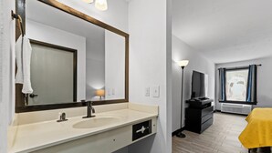 A bathroom with a large mirror, sink, and towel rack.
