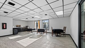 A spacious room with a tiled ceiling, a kitchen area with cabinets and appliances, and a dining area with tables and chairs.